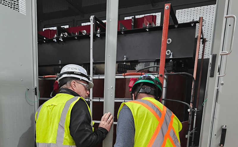 two service agents inspect cast coil transformer