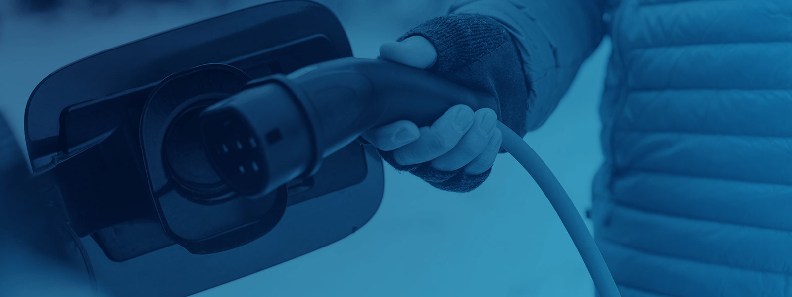 gloved hand plugs in an EV in the winter